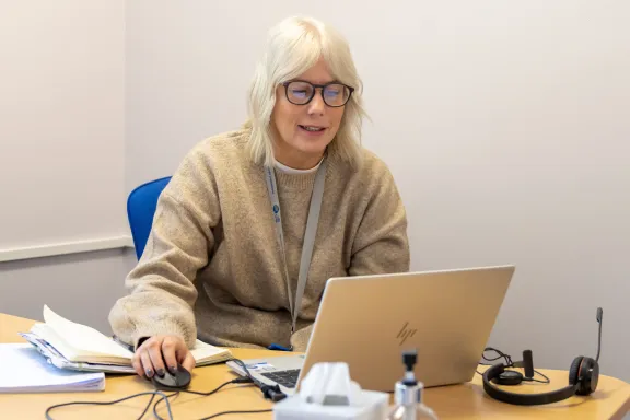 A blonde female adviser working on a laptop at a desk
