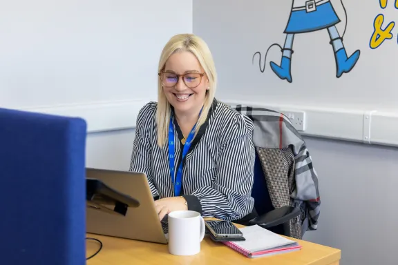 Female Adviser working on a laptop and smiling. 