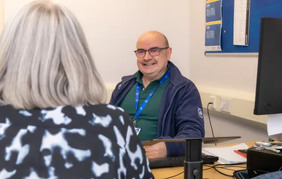 Male adviser talking to a client. Female clients back of head is visible in the image. 