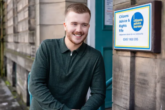 A male adviser smiling at the front entrance of an office
